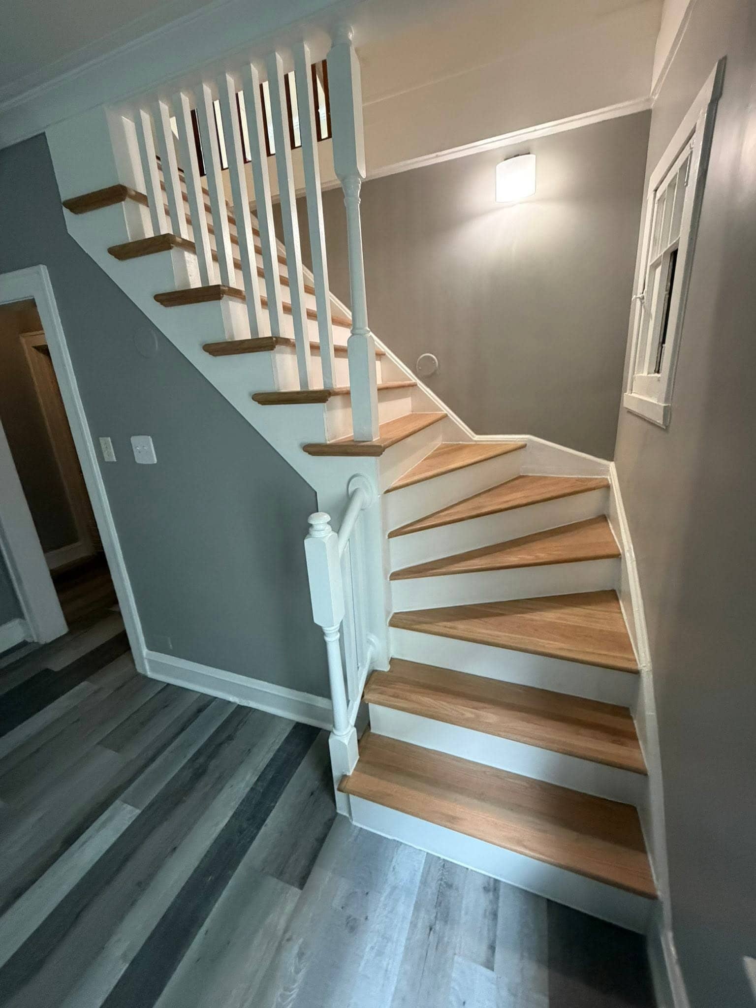 Refinished wood staircase with white risers and railing