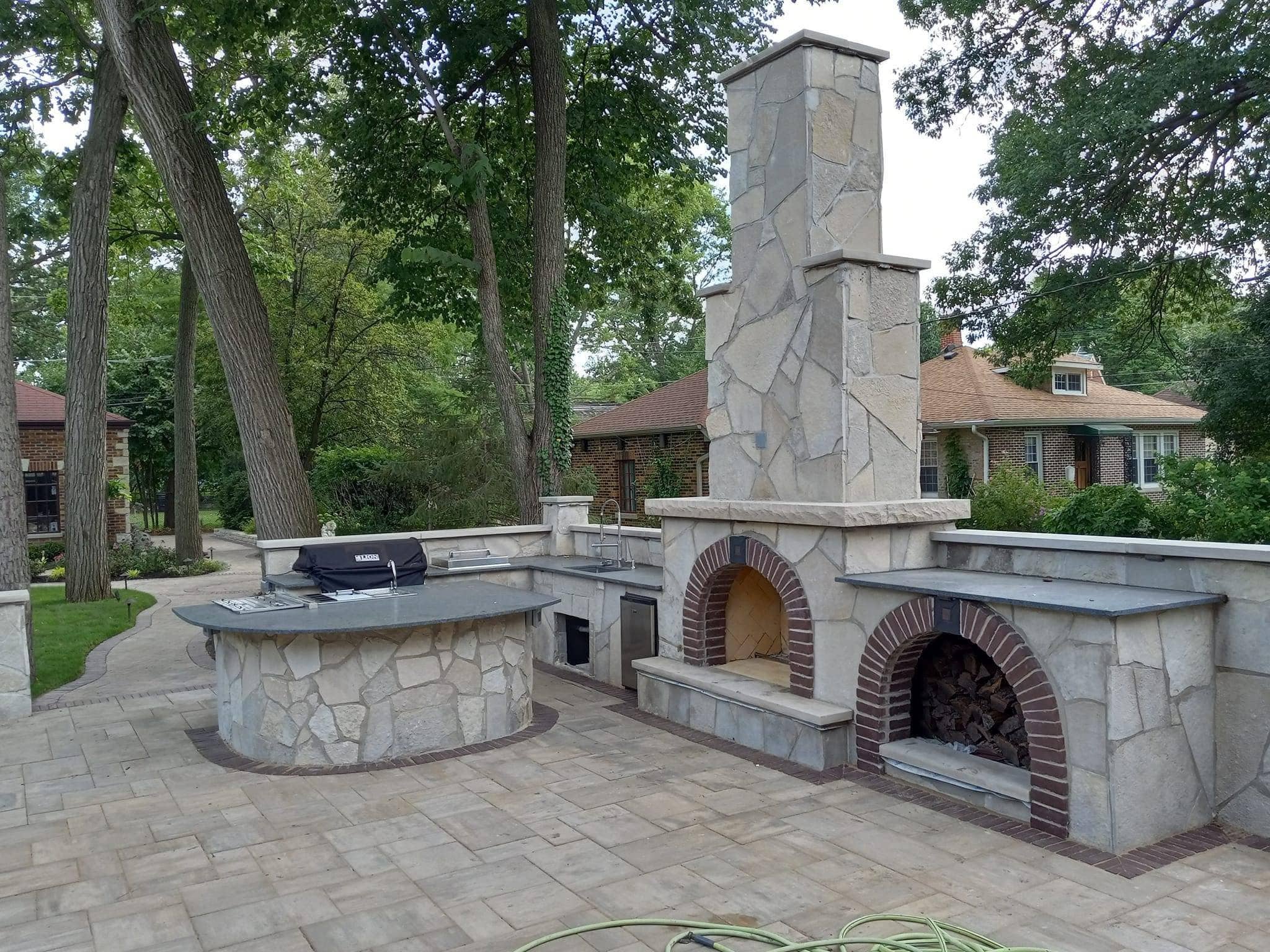 Large stone outdoor kitchen with a tall fireplace chimney