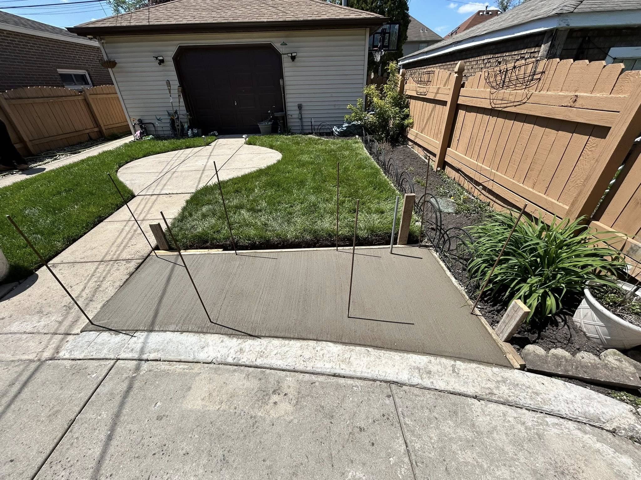New concrete walkway with freshly laid sod and a garden bed